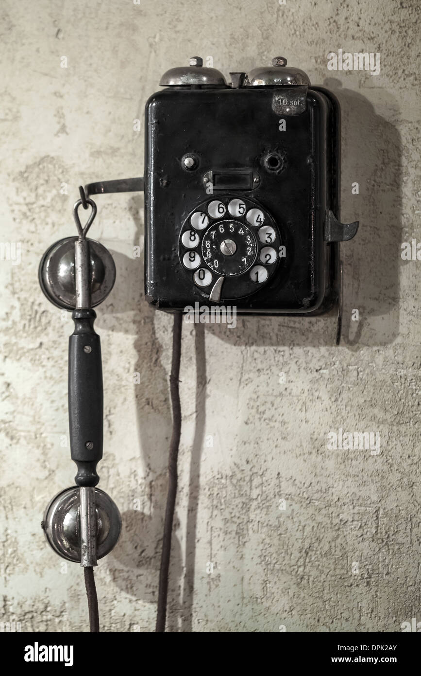 Vintage black phone hanging on old gray concrete wall Stock Photo