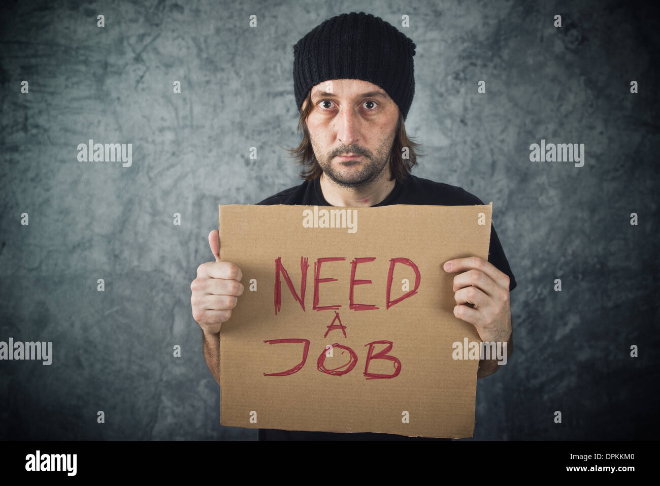 Man holding cardboard paper with Need a Job message. Job seeking, unemployment issues. Stock Photo