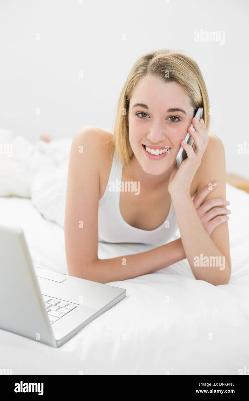 Beautiful blonde woman phoning peacefully lying on her bed Stock Photo