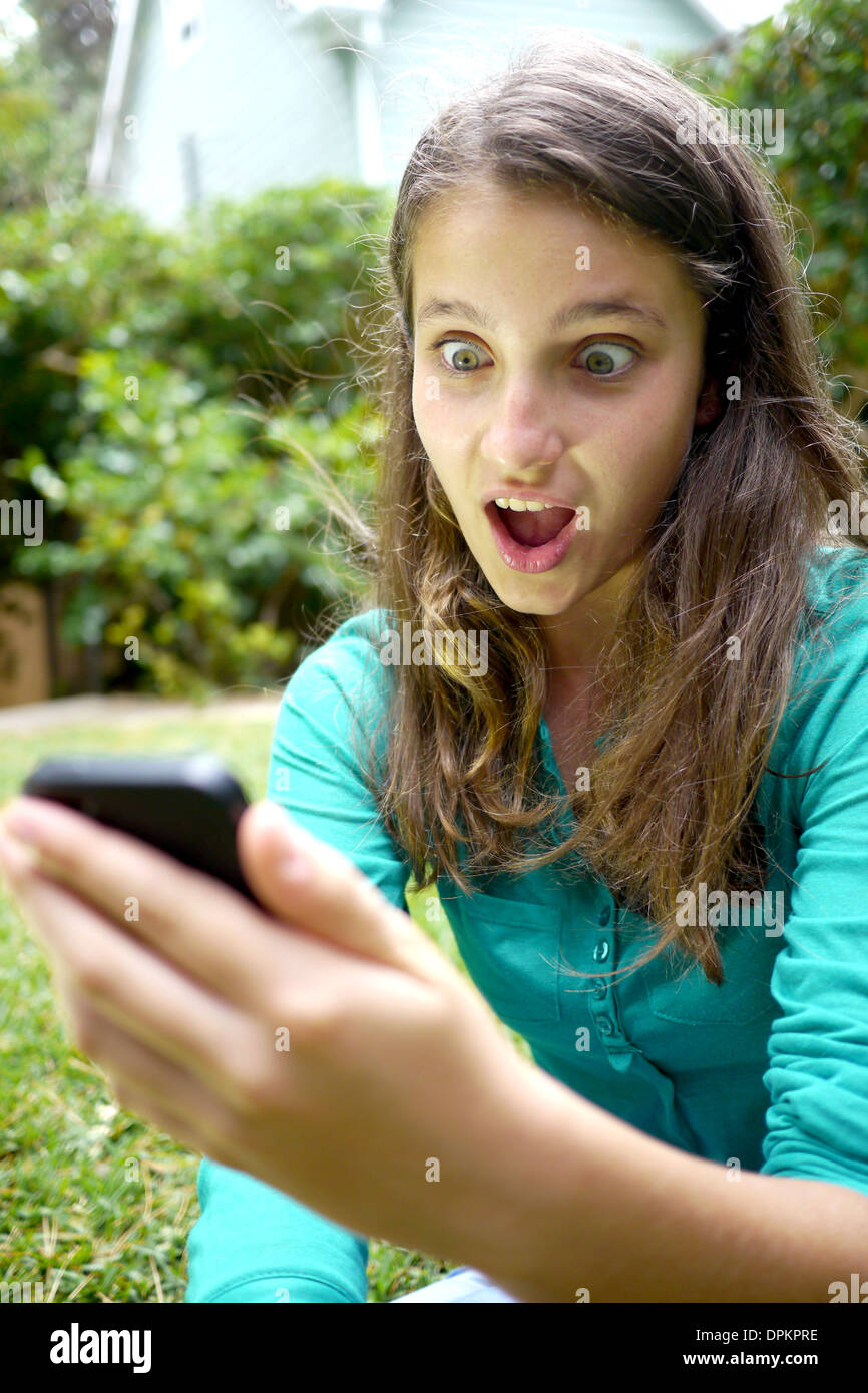 girls gets shock at text message on cellphone Stock Photo