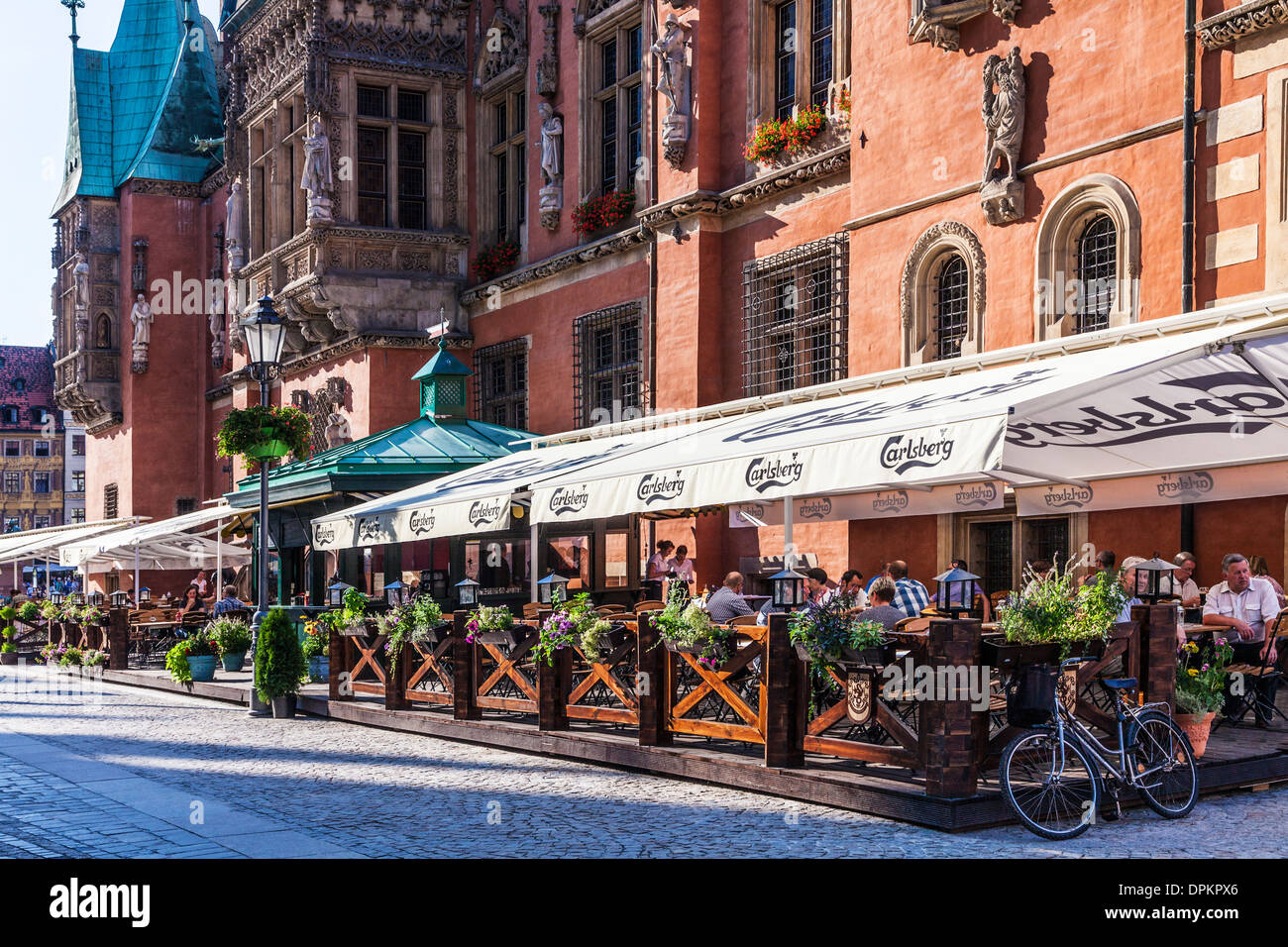 Outdoor restaurant bar beneath the neo-Gothic Town Hall or Ratusz in Wroclaw's market Square. Stock Photo