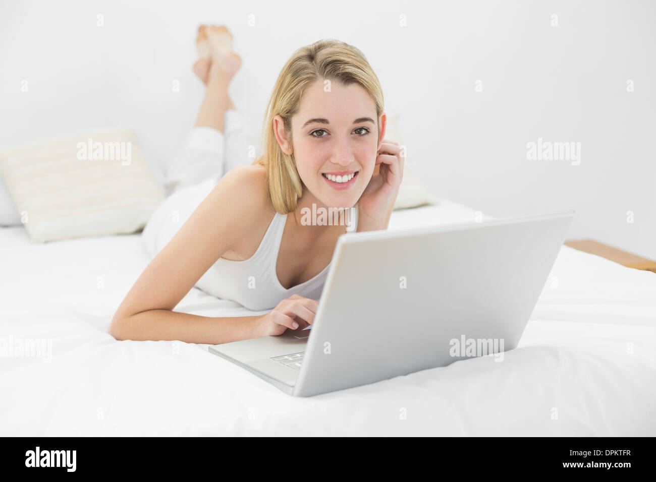 Beautiful woman lying on her bed using her laptop Stock Photo