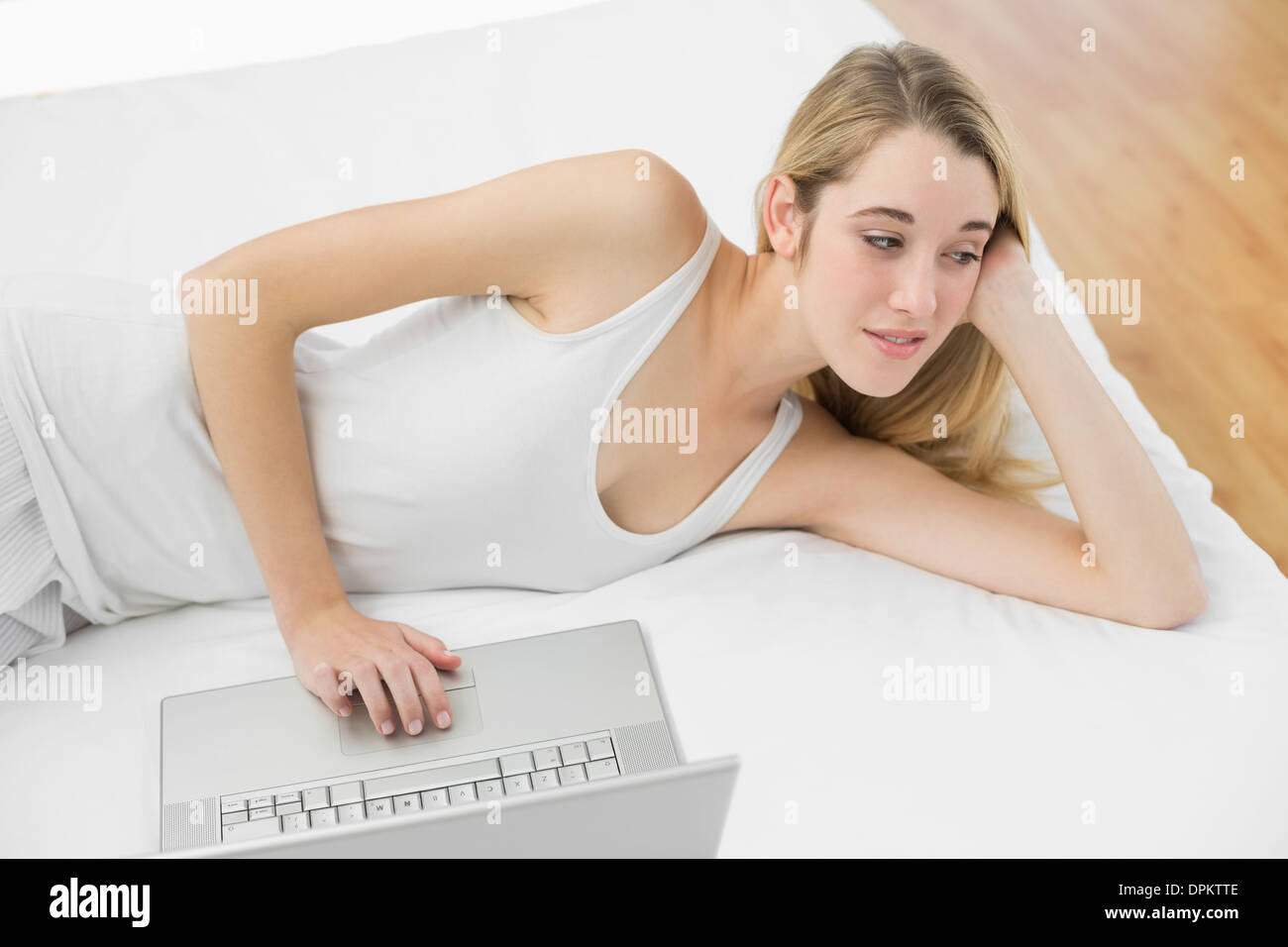 Thoughtful calm woman using her notebook lying on her bed Stock Photo