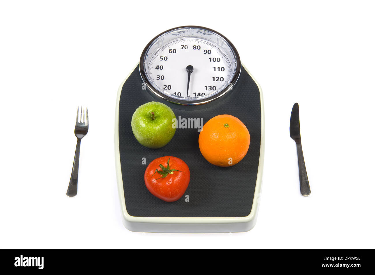 A weight scale with fruit a fork and a knife Stock Photo