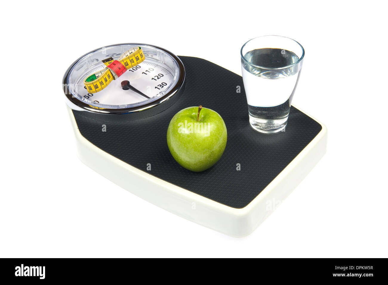 A weight scale with measuring tape, an apple and a glass of water Stock Photo