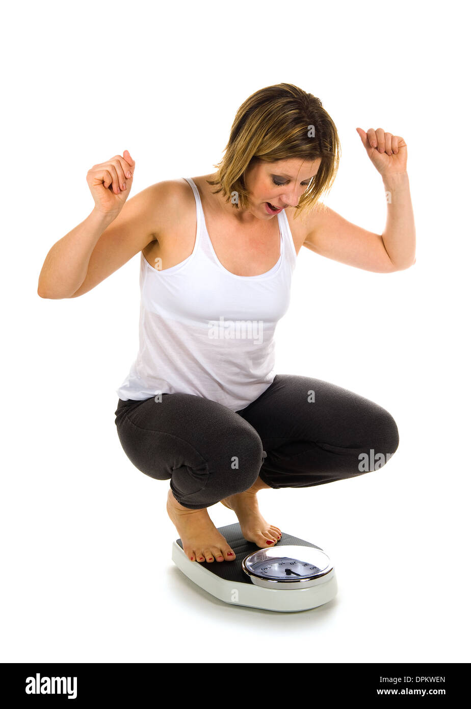A woman is sitting on a weight scale and is satisfied about her weight Stock Photo