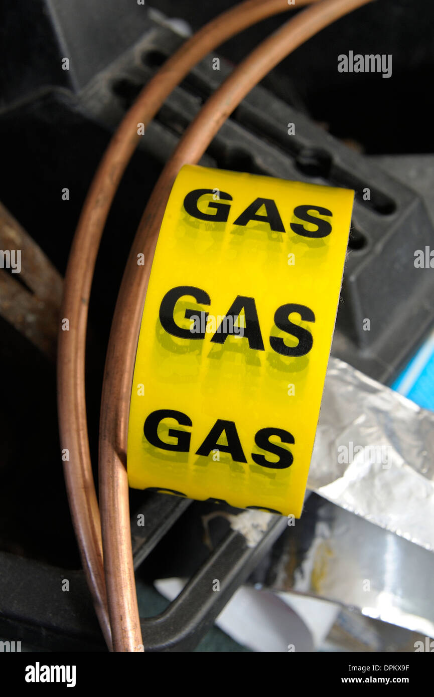 yellow gas safety tape with some copper pipe Stock Photo