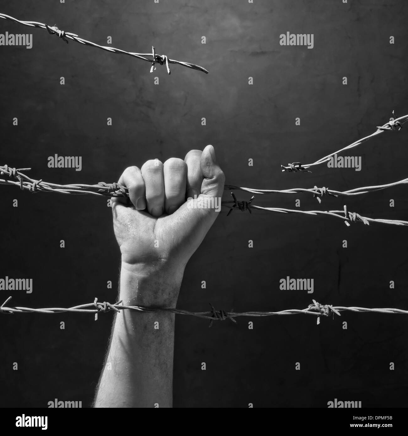 hand behind barbed wire with dark background Stock Photo