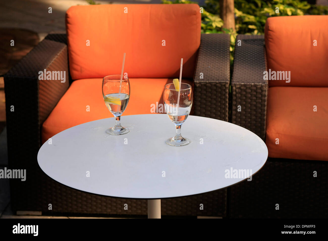 Drinks glasses sitting on a white table with relaxing style chair at an al Fresco restaurant Stock Photo