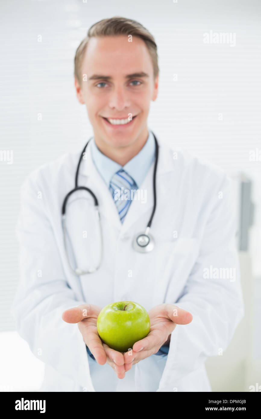 Portrait of a smiling male doctor holding a green apple Stock Photo - Alamy
