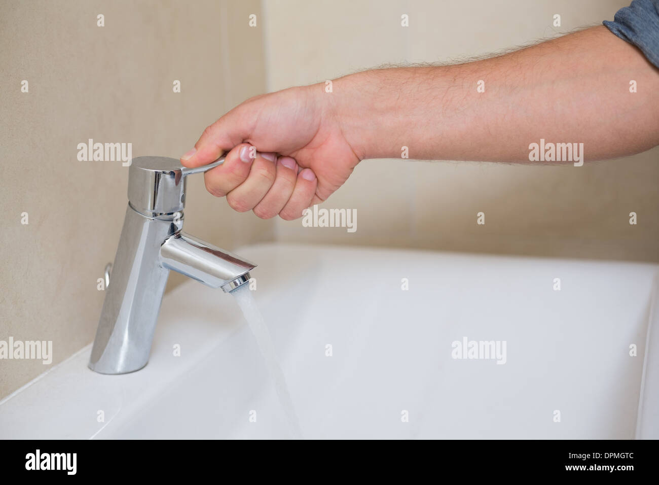 Plumbers hand opening a water tap at bathroom Stock Photo Alamy