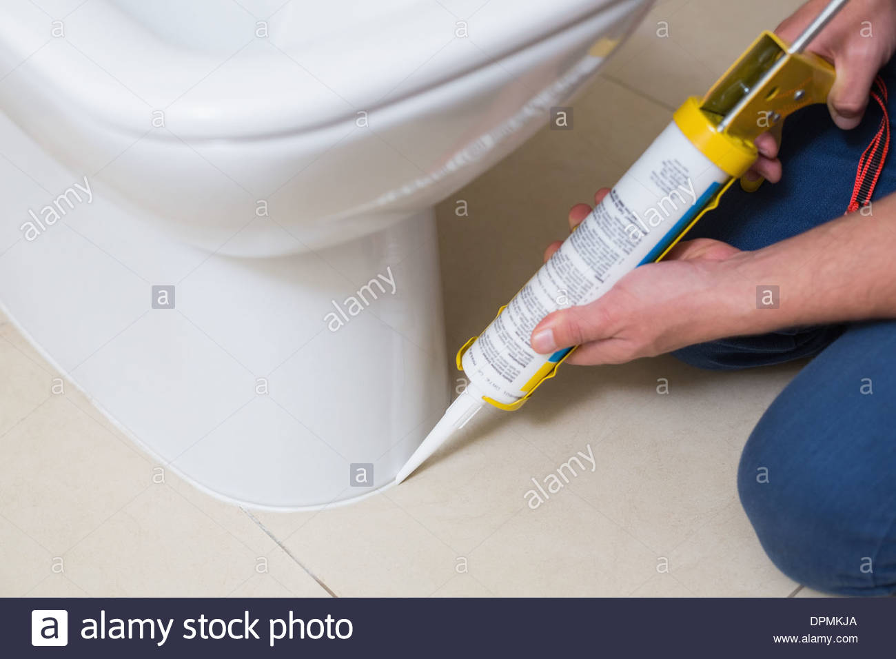 Plumber fixing toilet in a washroom with silicone cartridge Stock Photo