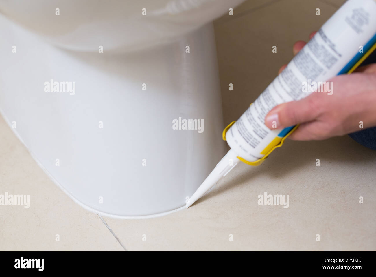 Plumber fixing toilet in a washroom with silicone cartridge Stock Photo