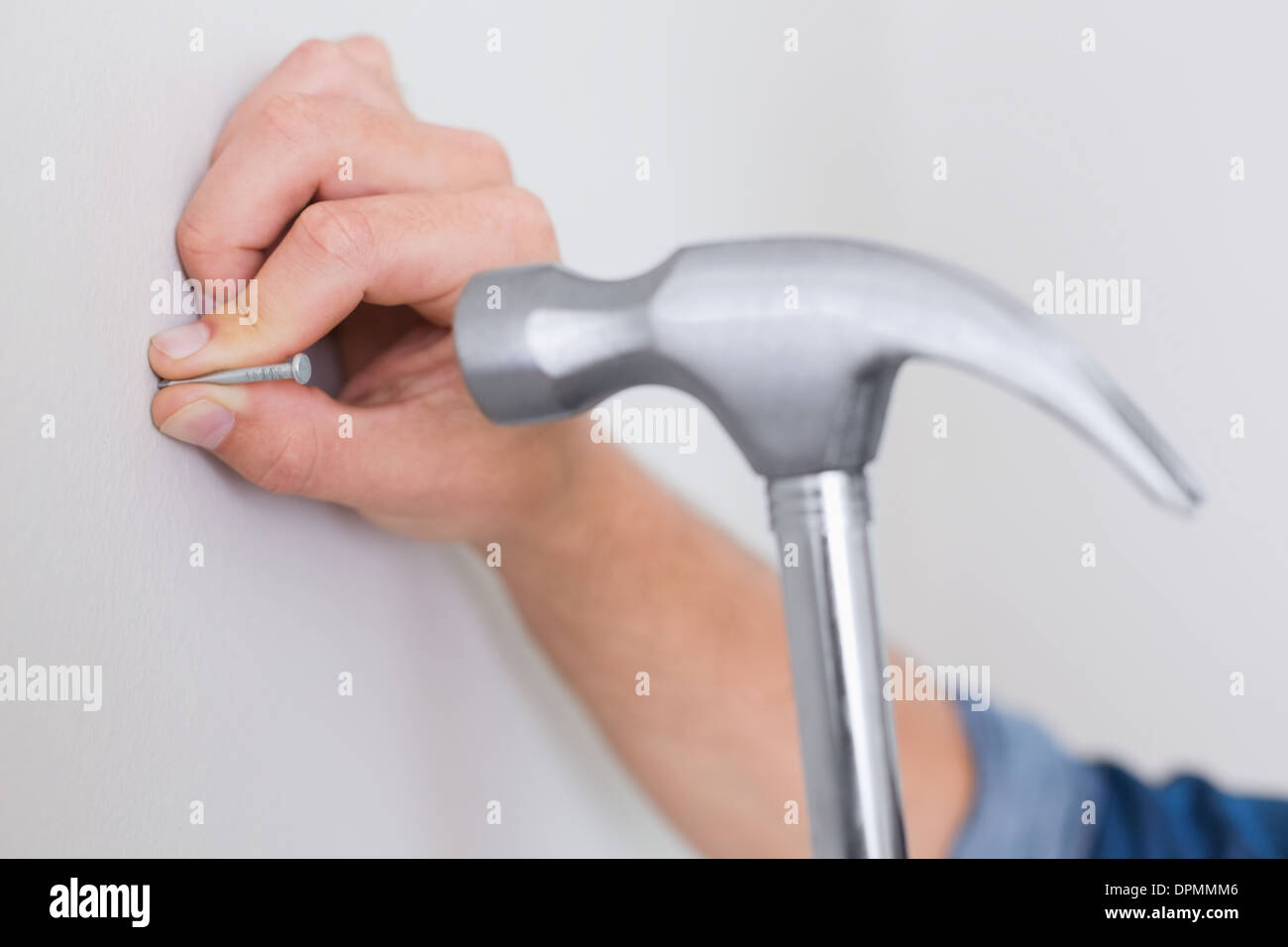 Hands hammering nail in wall Stock Photo Alamy