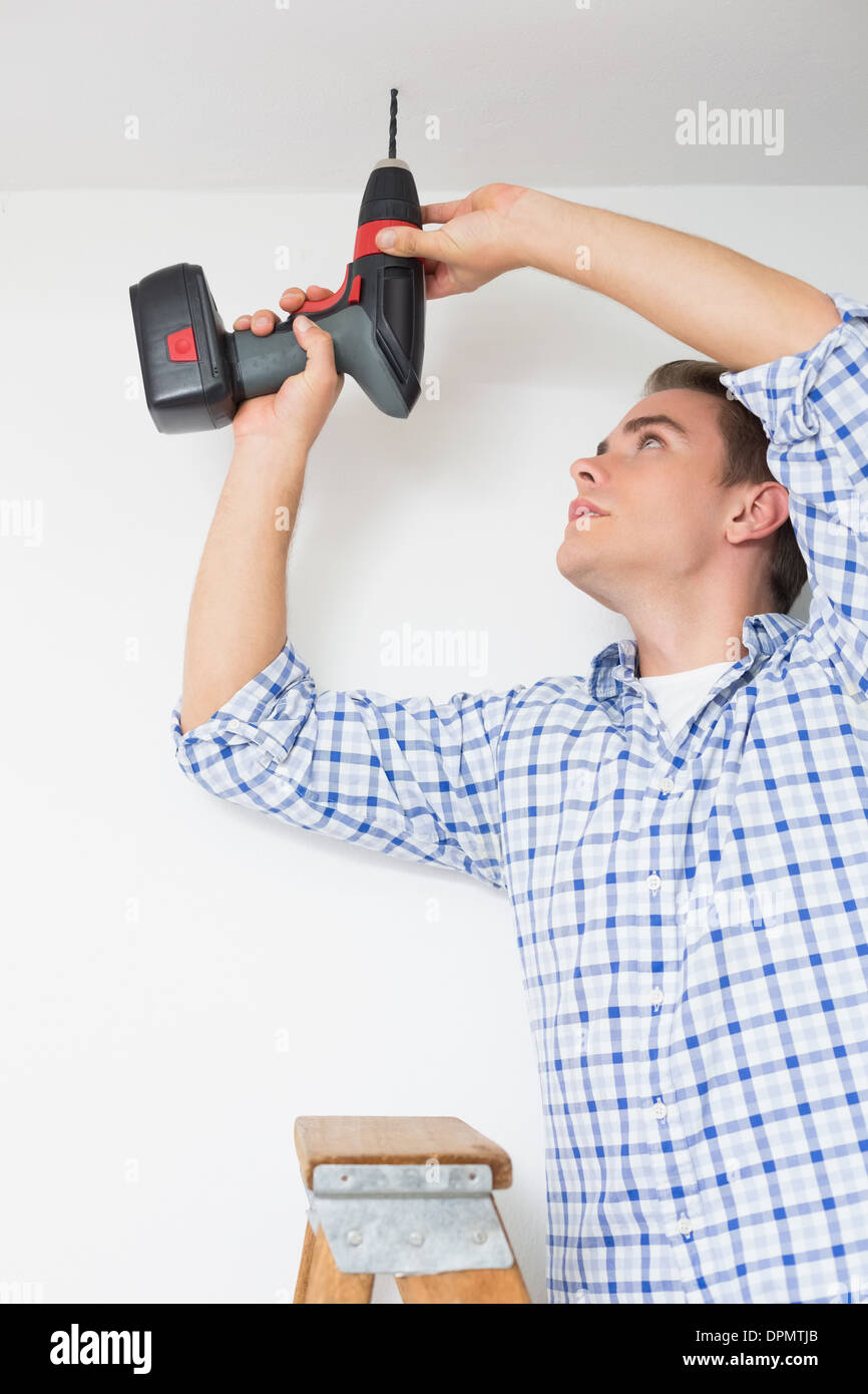Handyman using a cordless drill to the ceiling Stock Photo