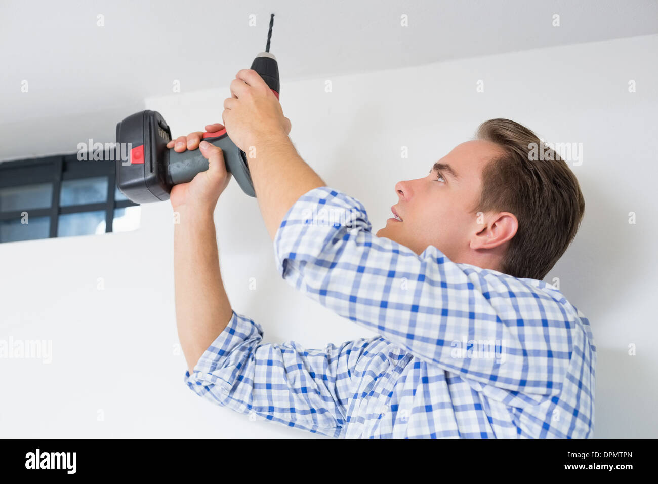 Handyman using a cordless drill to the ceiling Stock Photo