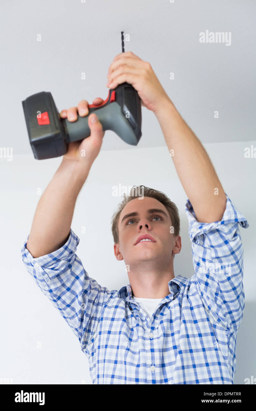 Handyman using a cordless drill to the ceiling Stock Photo