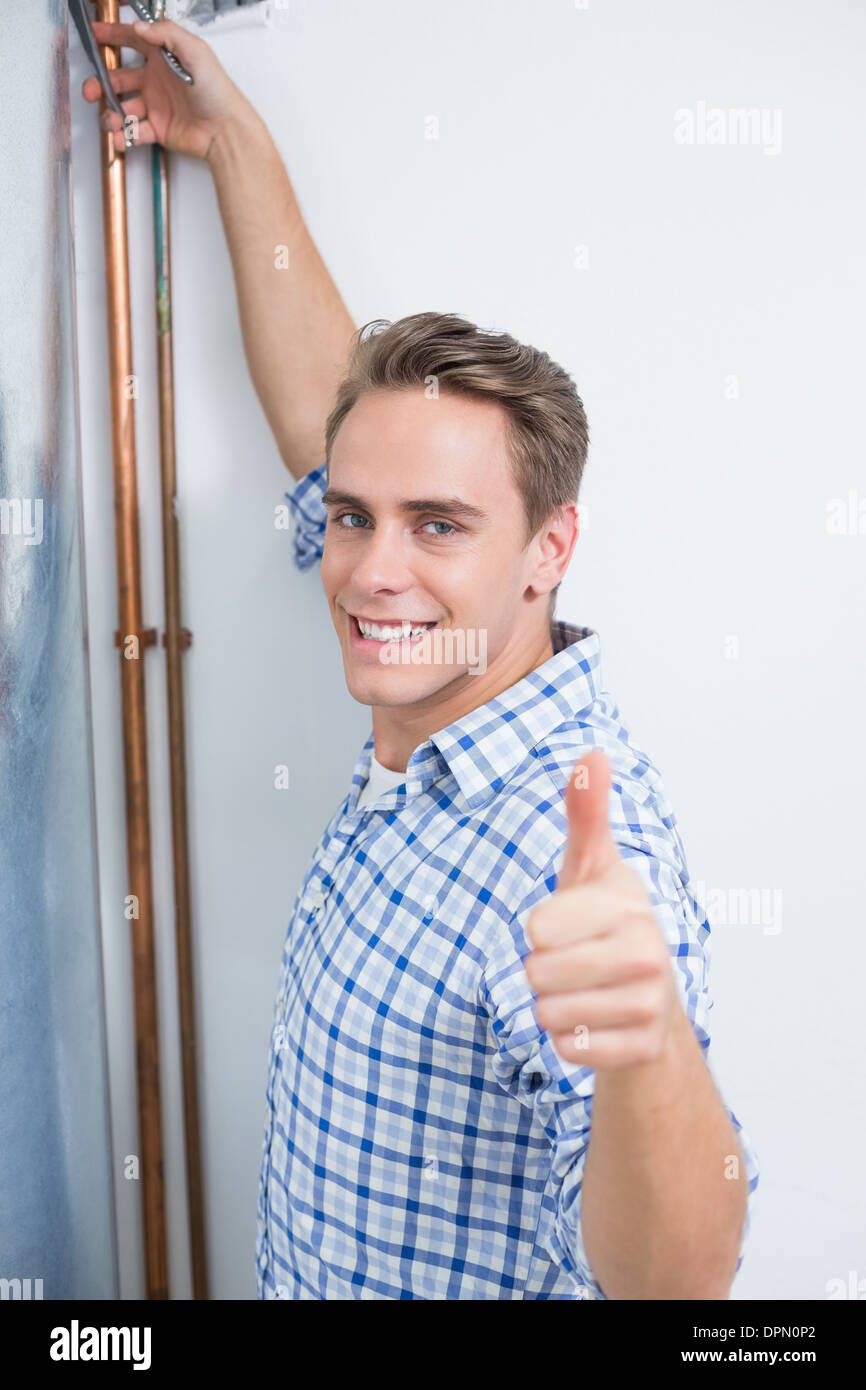 Technician gesturing thumbs up by hot water heater Stock Photo
