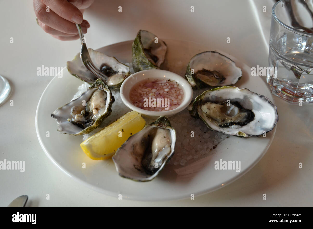 A woman's hand reaching for an oyster Stock Photo