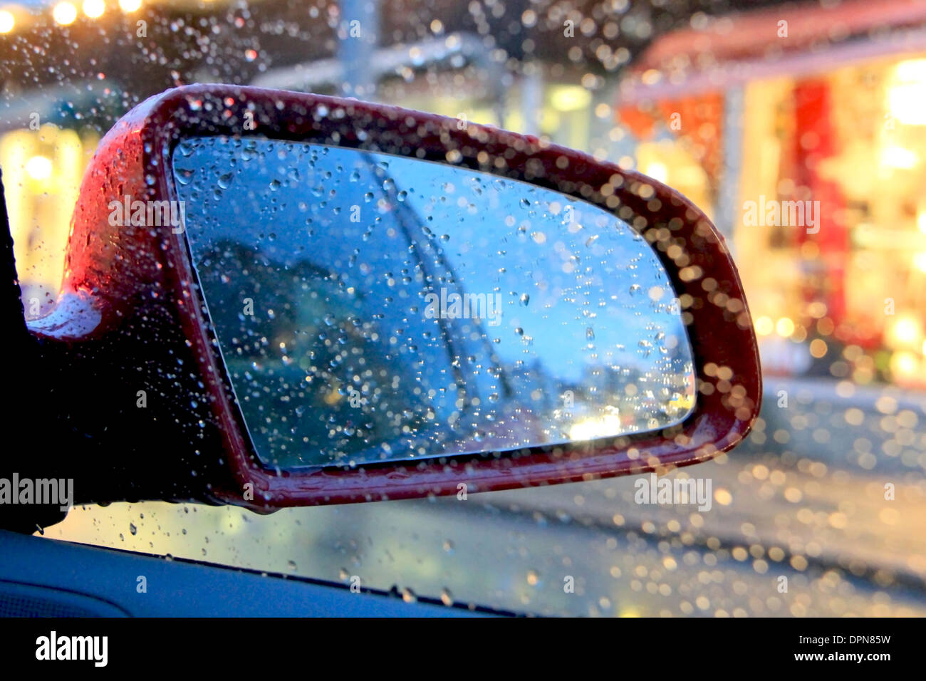 Abstract image of rain drops on car side view mirror and window. Stock Photo