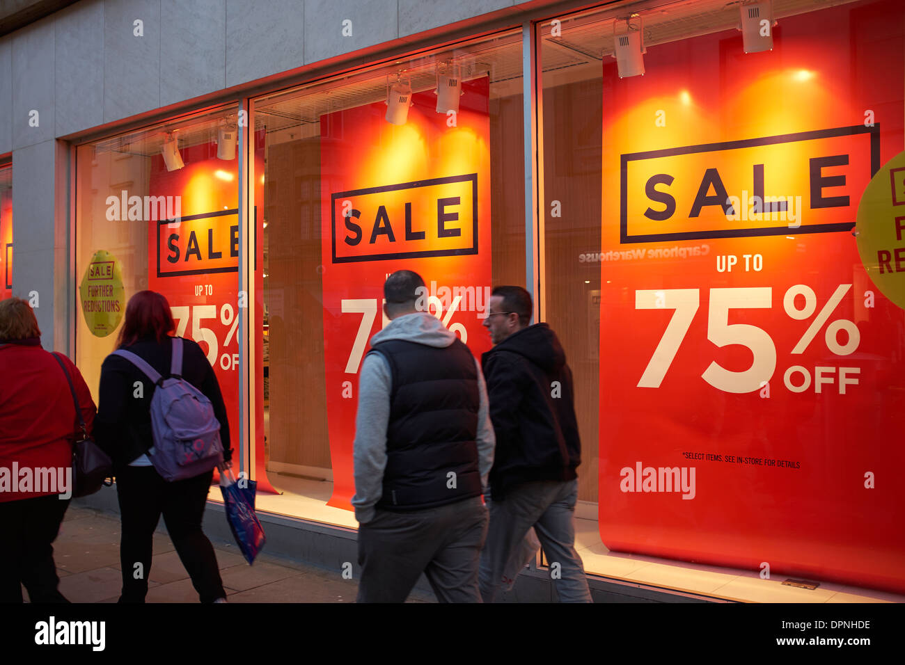 Shoppers walking past the sale banners in a shop window Stock Photo