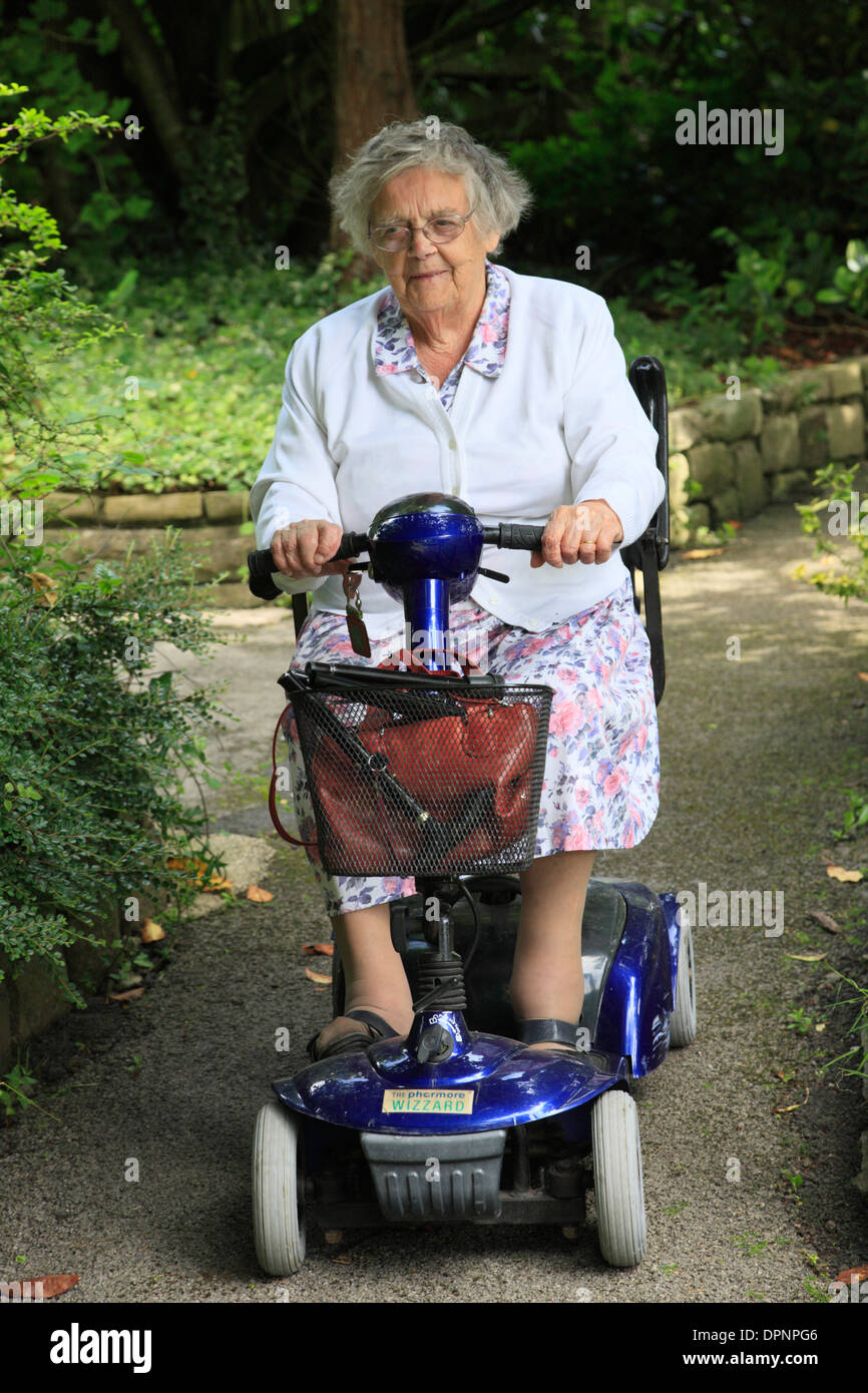 An old lady riding on a mobility scooter. Stock Photo