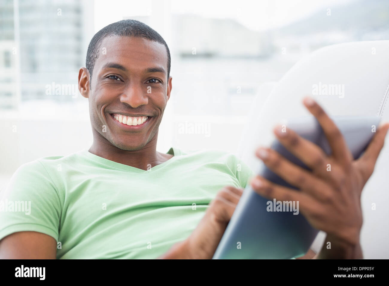 Casual smiling Afro man using digital tablet on sofa Stock Photo