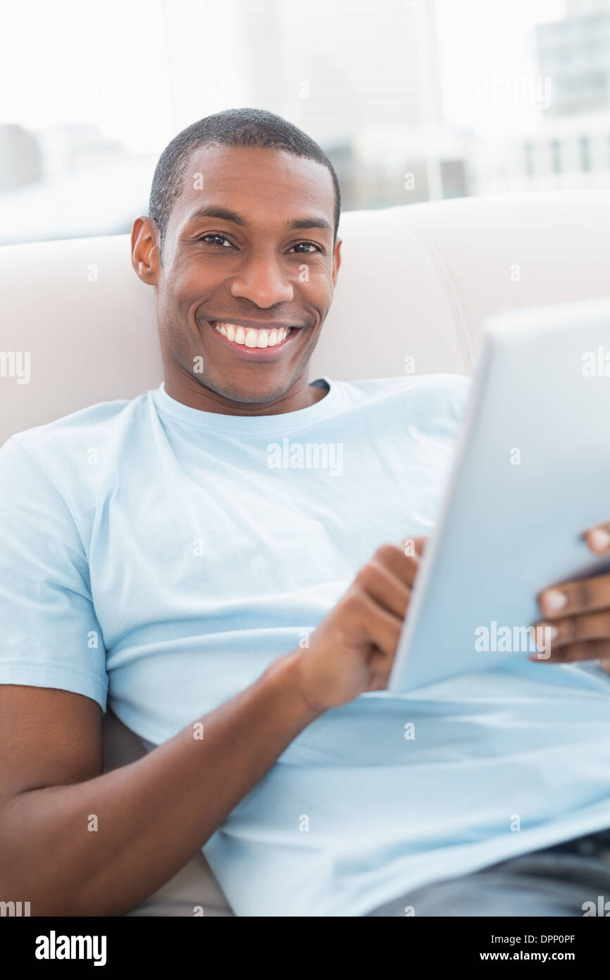 Casual smiling young Afro man using digital tablet on sofa Stock Photo