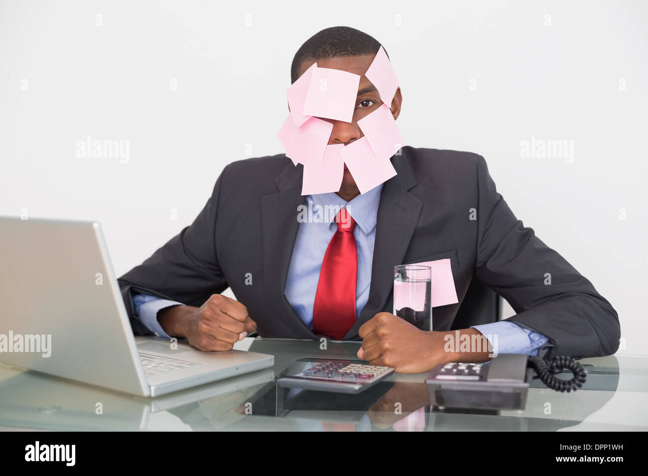Afro businessman with blank notes on face and laptop Stock Photo