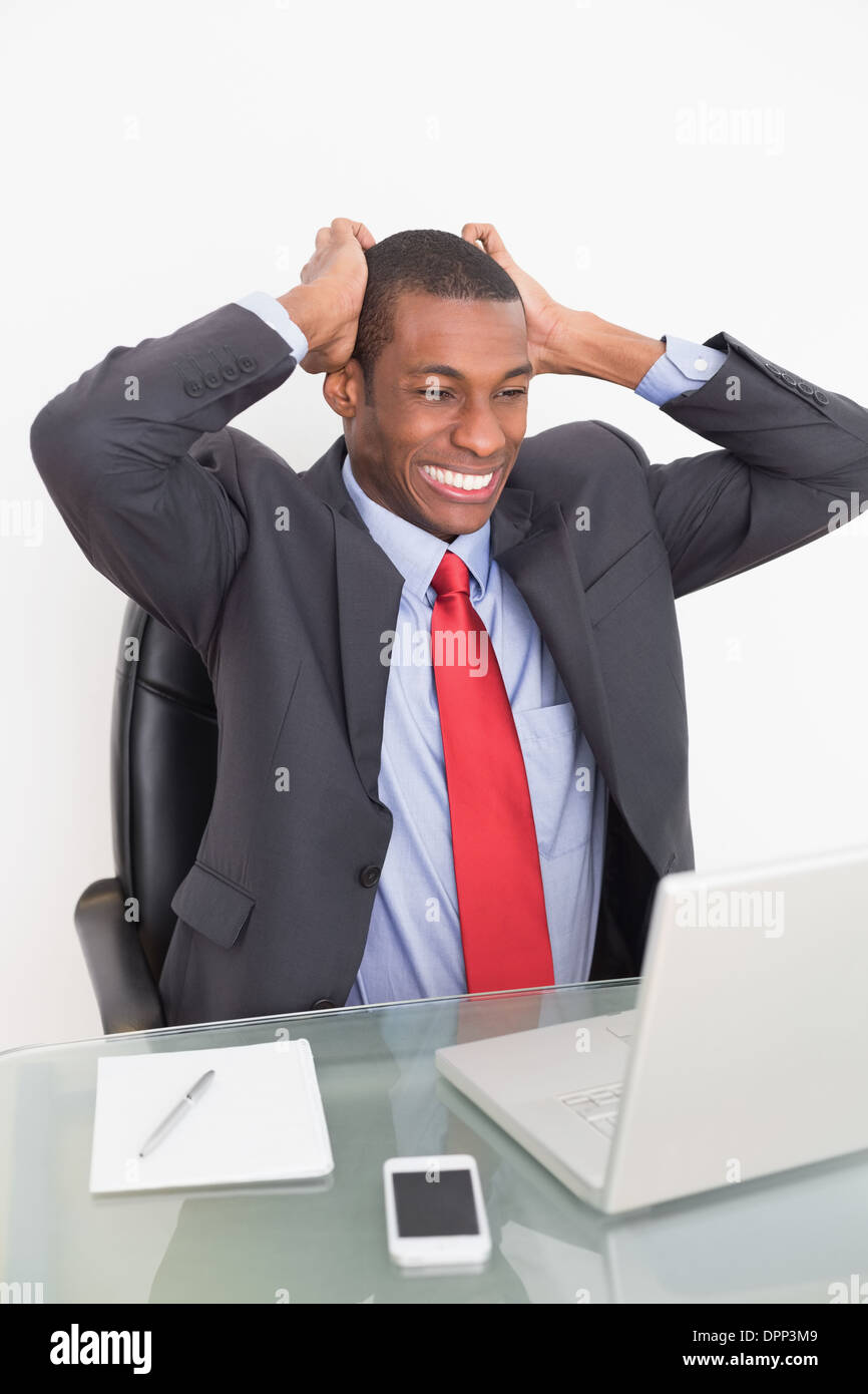 Frustrated Afro businessman looking at laptop at desk Stock Photo