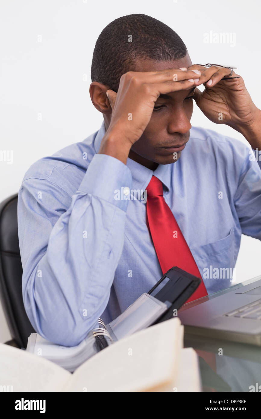 Frustrated Afro businessman with head in hands at desk Stock Photo