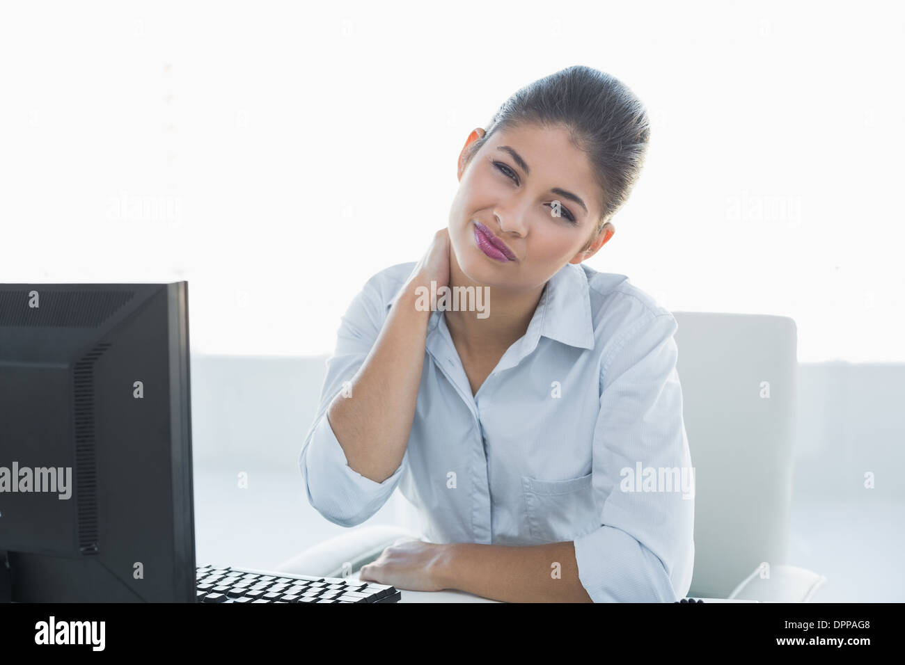 Businesswoman with neck pain in front of computer Stock Photo