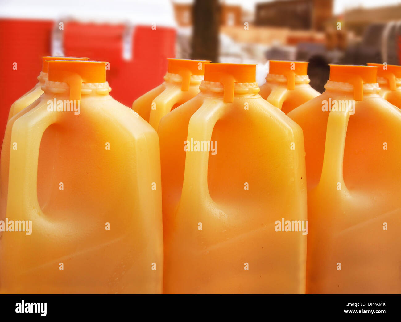 Many jugs of orange juice set up on a catering table at an outdoor event. Stock Photo
