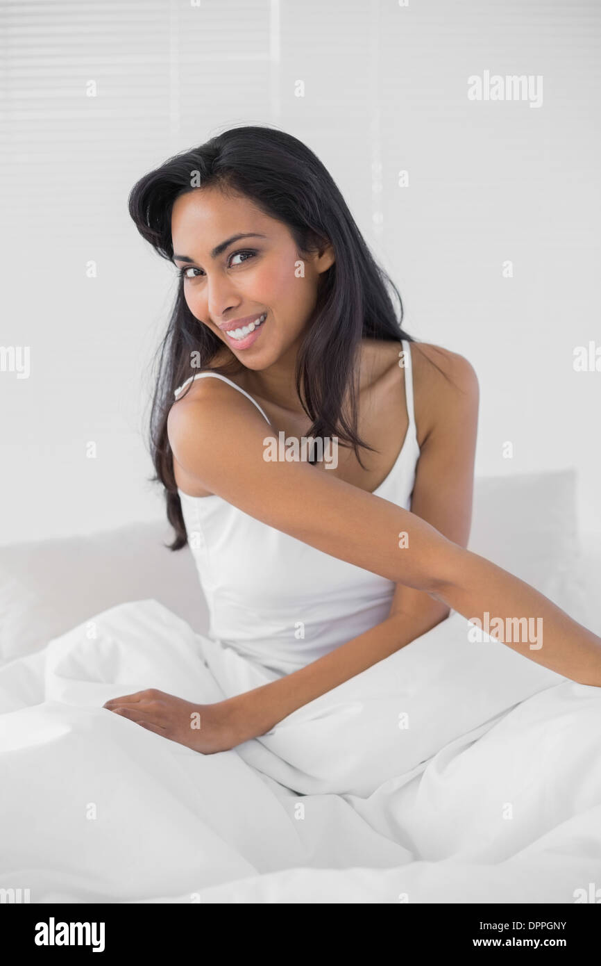 Cute woman smiling cheerfully at camera sitting on her bed Stock Photo ...