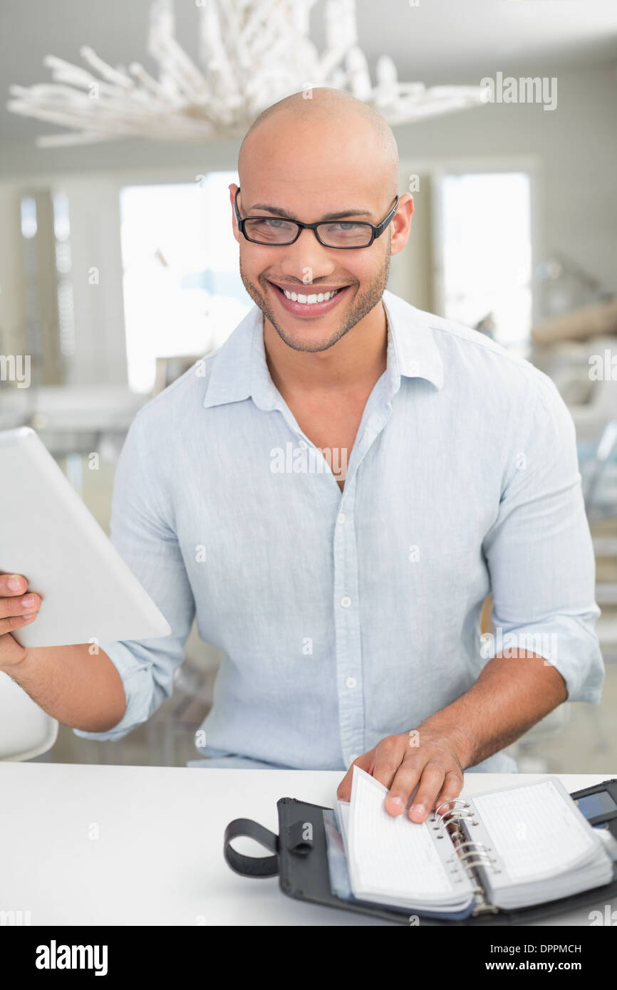 Casual smiling man with digital tablet and diary at home Stock Photo