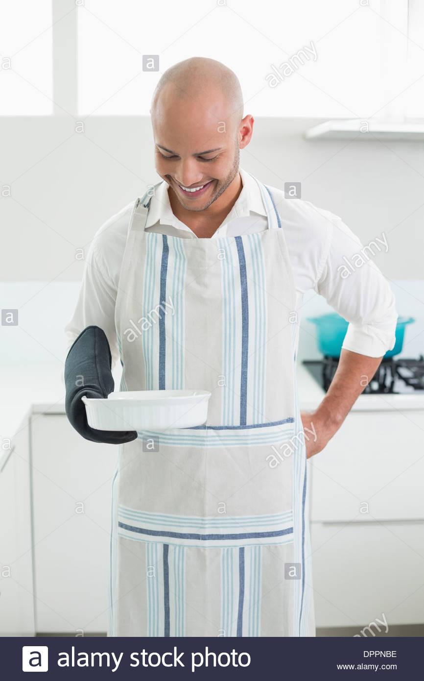 Smiling man holding a baking dish in kitchen Stock Photo