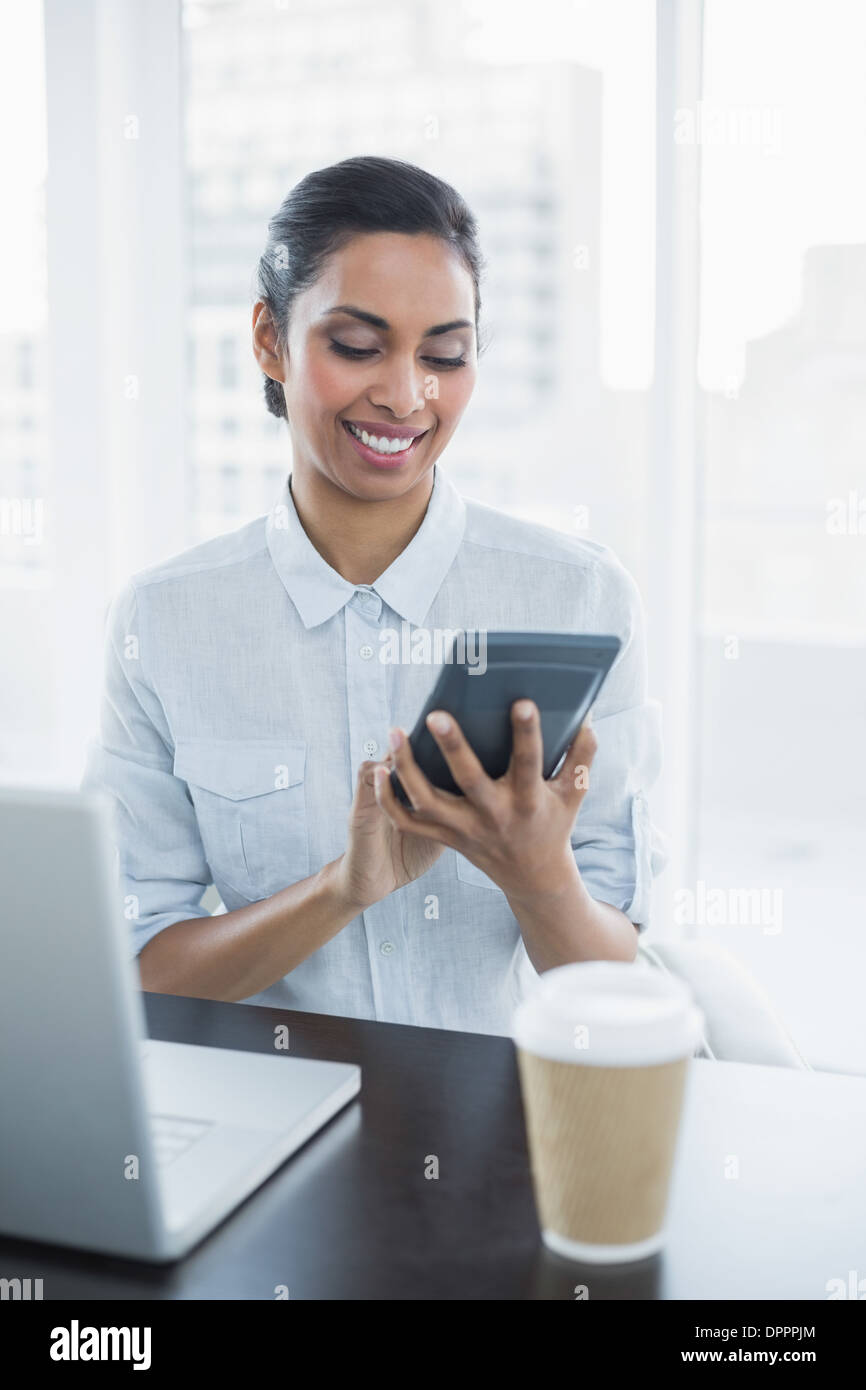 Content businesswoman using a calculator sitting at her desk Stock Photo