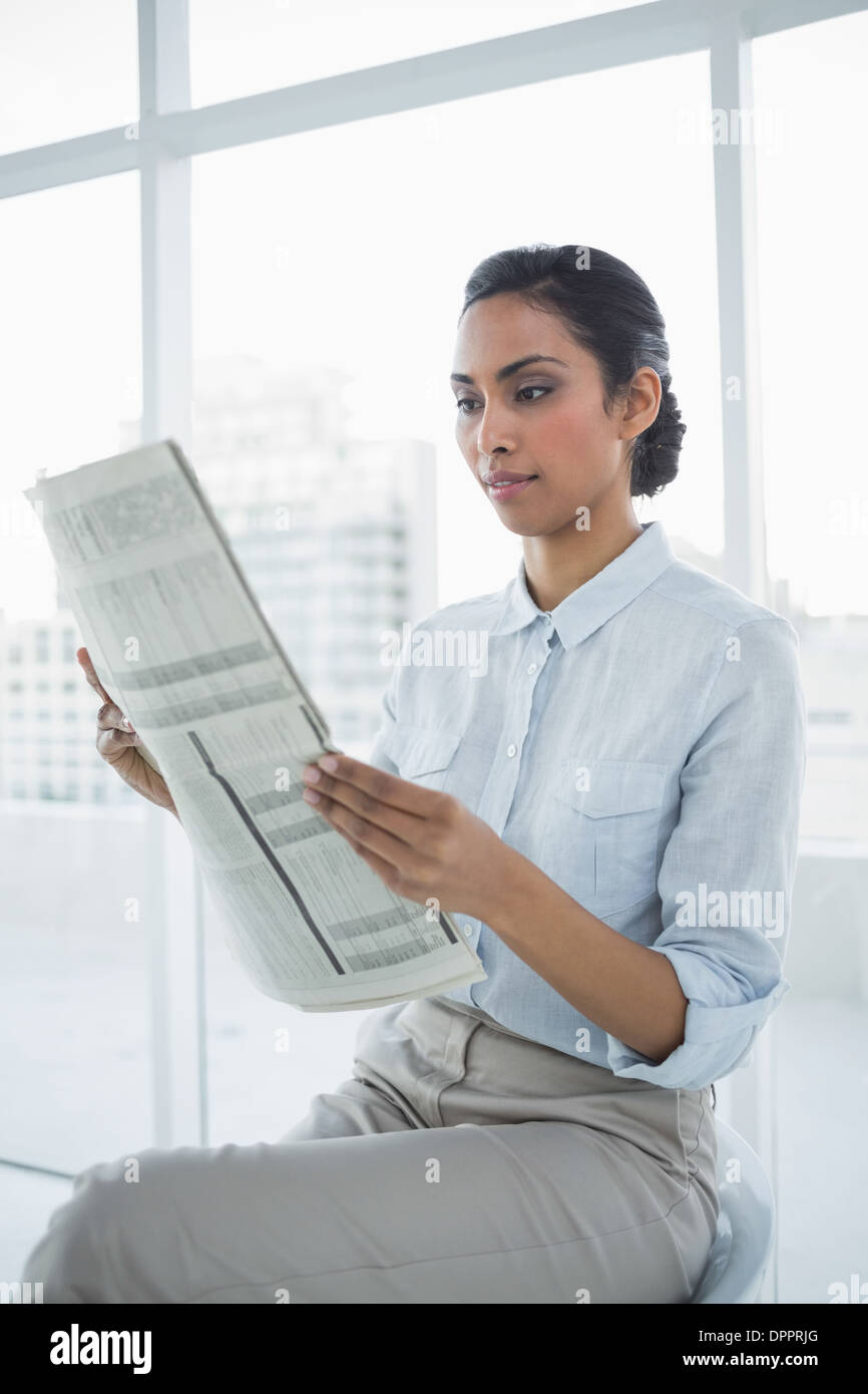 Softly smiling chic businesswoman reading newspaper Stock Photo - Alamy