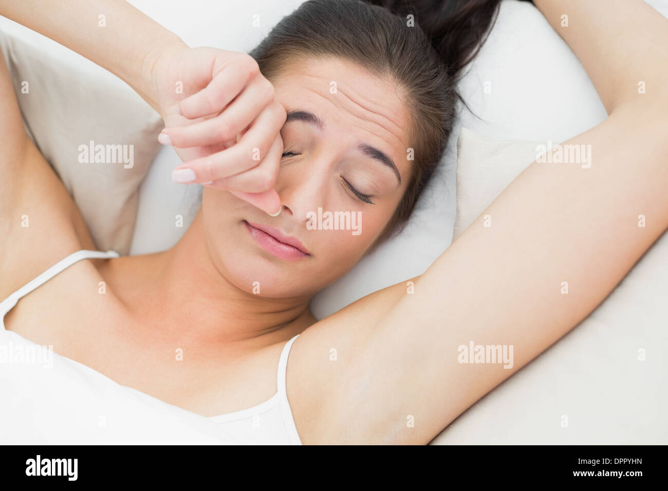 Beautiful woman rubbing eye in bed Stock Photo