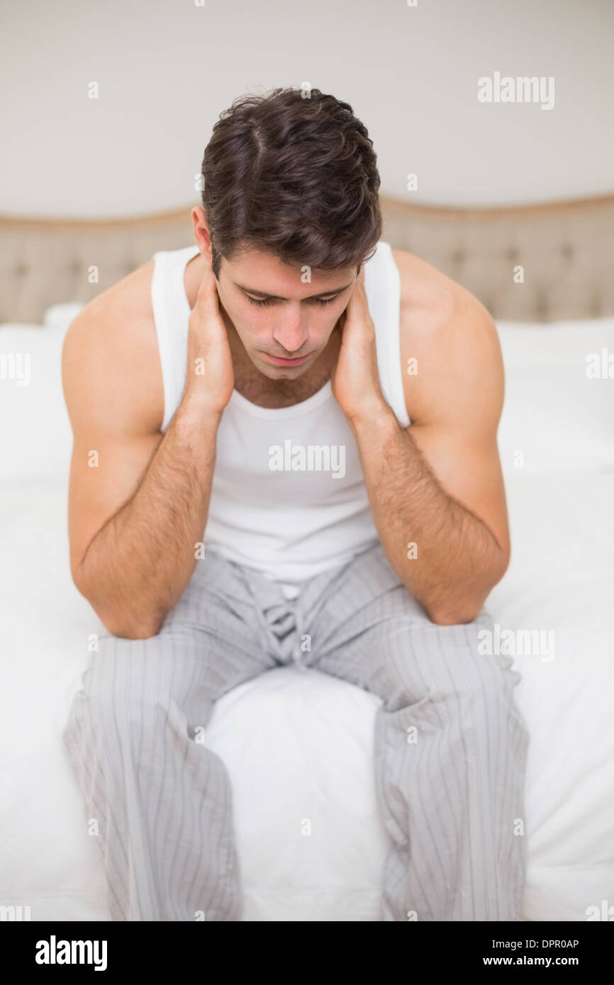 Thoughtful young man sitting in bed Stock Photo