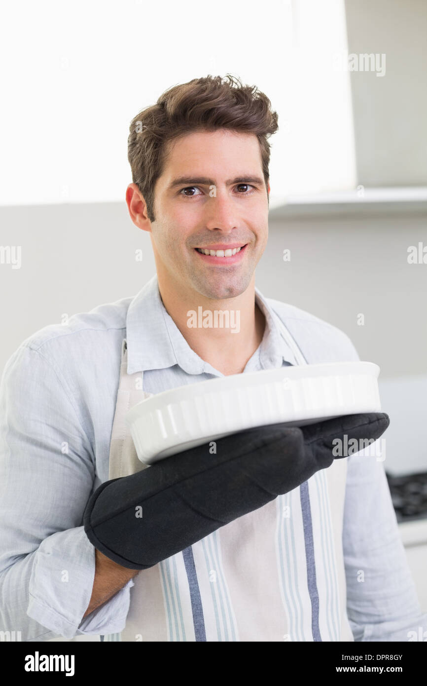 Smiling man holding a baking dish in kitchen Stock Photo