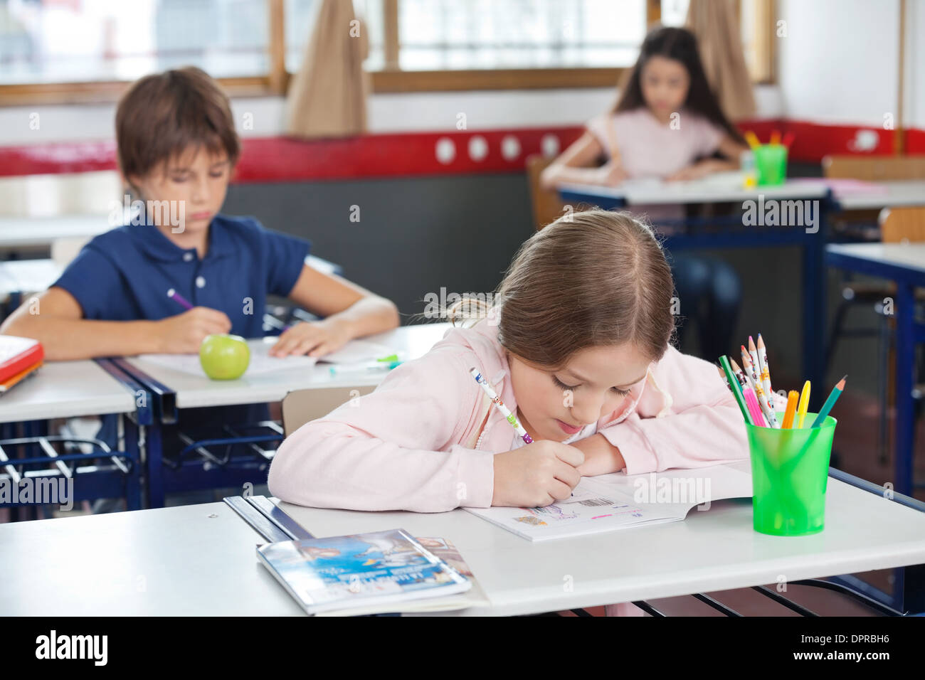 Schoolgirl Drawing While Leaning On Desk In Classroom Stock Photo - Alamy