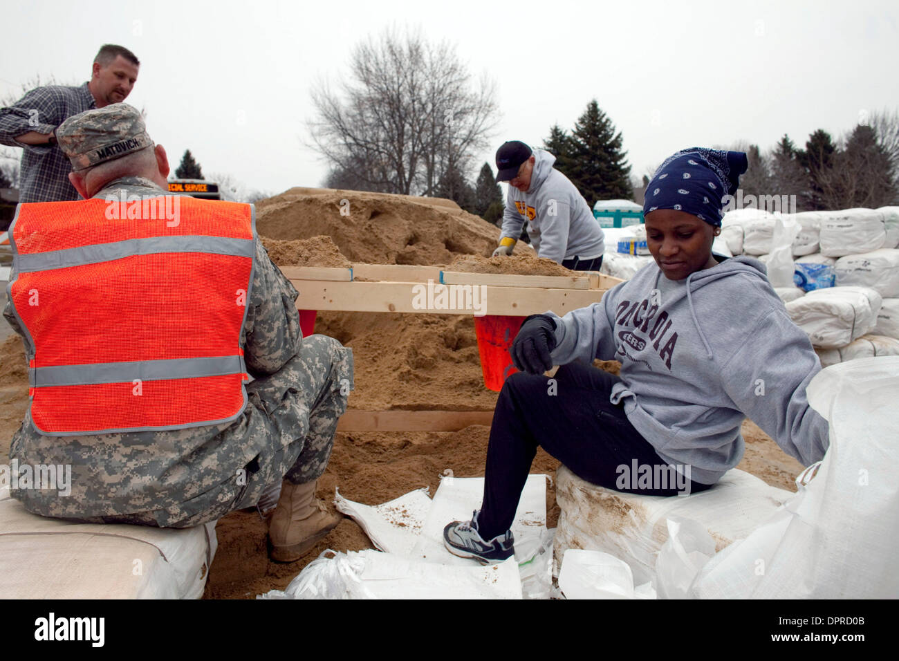 March 22, 2009 - Moorhead, Minnesota, USA - Concordia College student NAI MUNGAYEH, right, fills sandbags with other volunteers and Minnesota Army National Guard troops in a neighborhood along the Red River in Moorhead, Minn. The Red River along the North Dakota and Minnesota border is expected to crest at or near record levels in the coming week. Residents on both sides of the riv Stock Photo