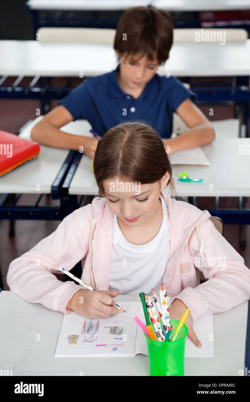 Schoolgirl Drawing At Desk In Classroom Stock Photo - Alamy