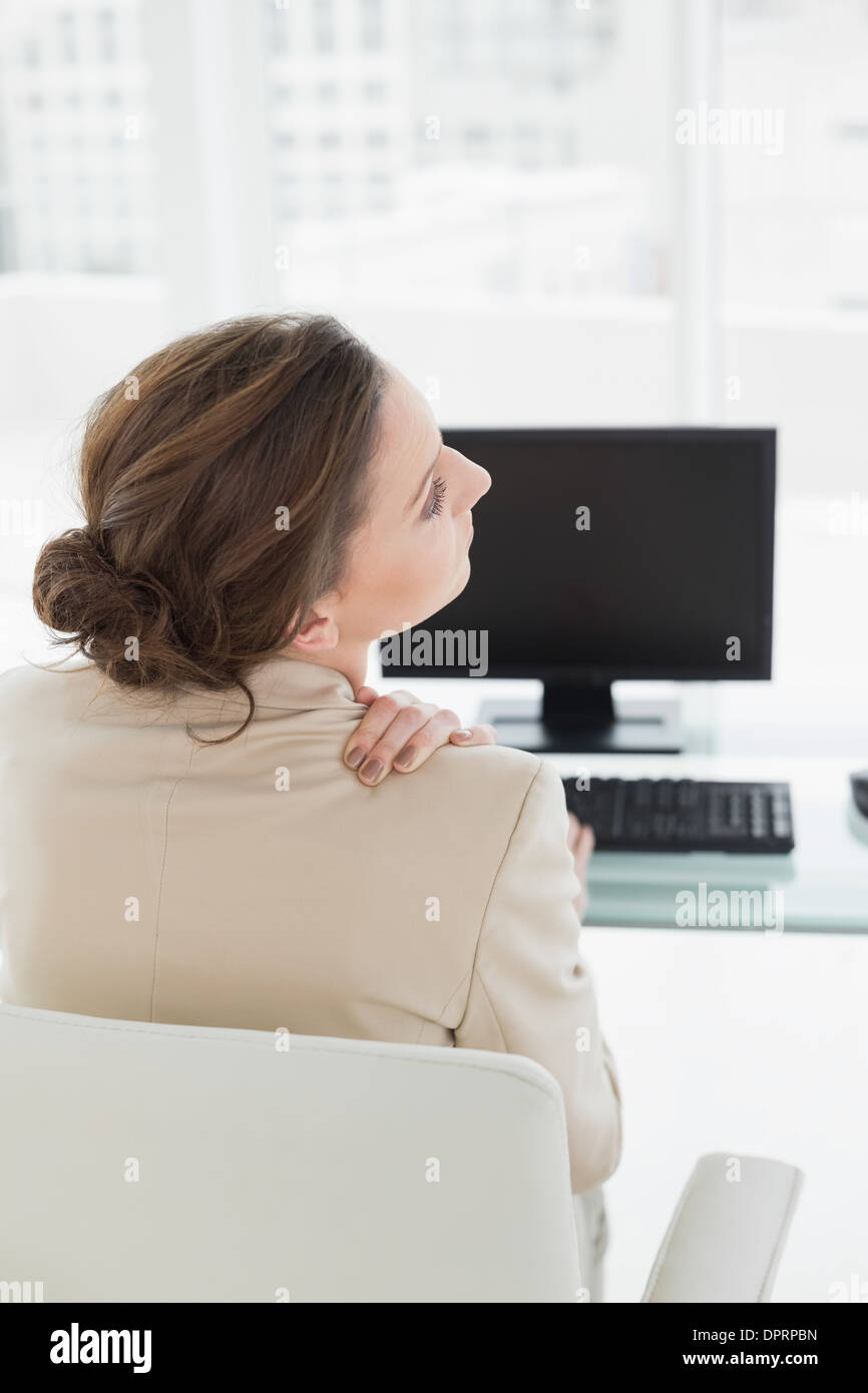 Businesswoman with neck pain in front of computer in office Stock Photo