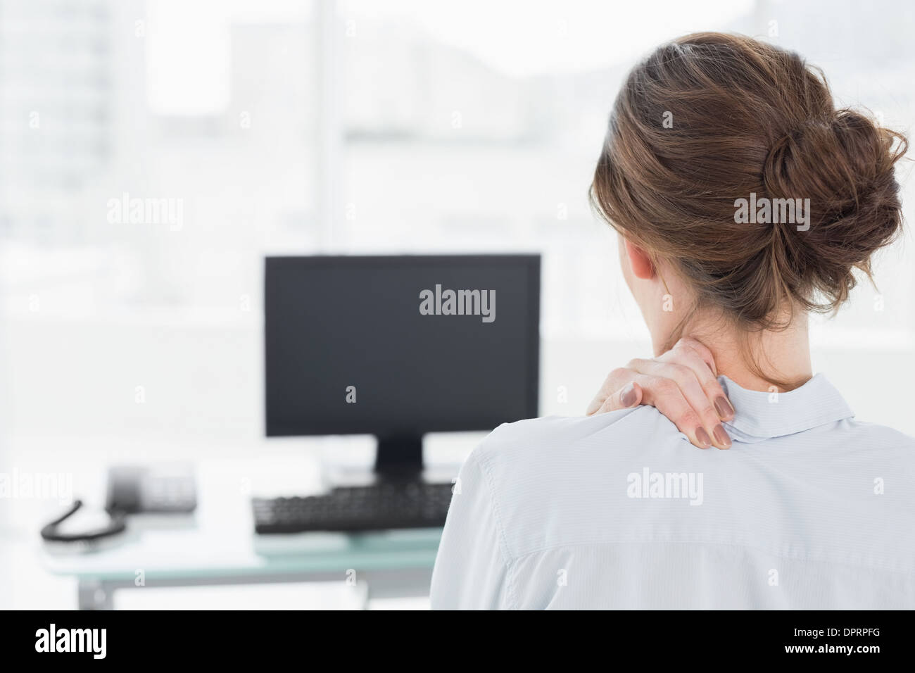 Rear view of a businesswoman with neck pain in office Stock Photo - Alamy