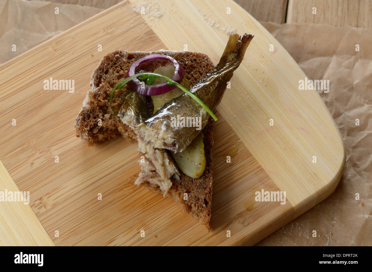 Unfinished sprat and onion open sandwich on the cut board Stock Photo