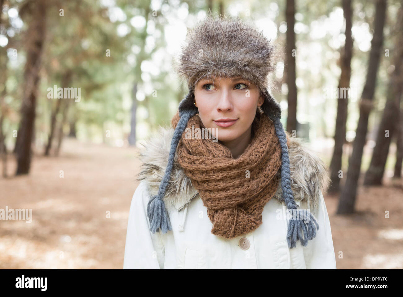 Woman wearing fur hat with woolen scarf and jacket in woods Stock Photo