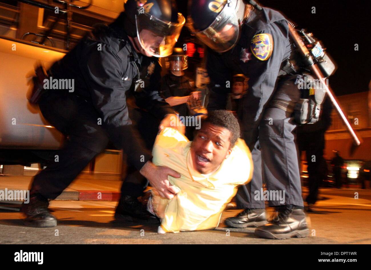 Police take a protester into custody along Fourteenth Street in Oakland, Calif., on Wednesday, January 7, 2009. Demonstrators from a protest against the fatal BART police shooting of Oscar Grant III took to Oakland streets Wednesday night blocking traffic, setting fires and damaging property. Scores of police, including BART police, Oakland Police Department and officers from the H Stock Photo