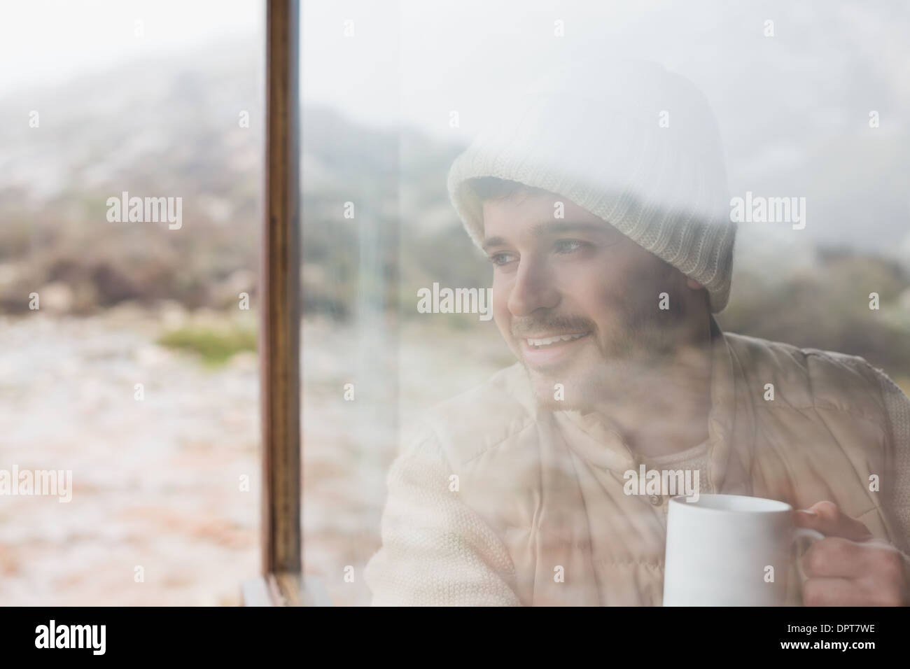 Thoughtful man with cup looking out through window Stock Photo